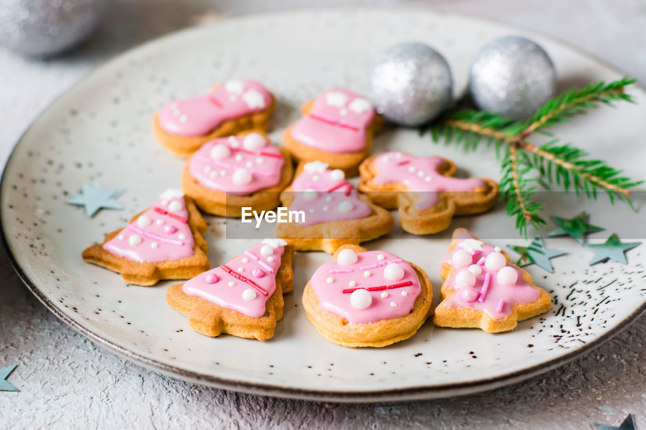 Christmas cookies with pink icing in a plate on the table. festive treat. close-up