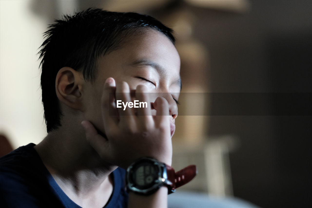 Close-up of boy wearing wrist watch sleeping indoors