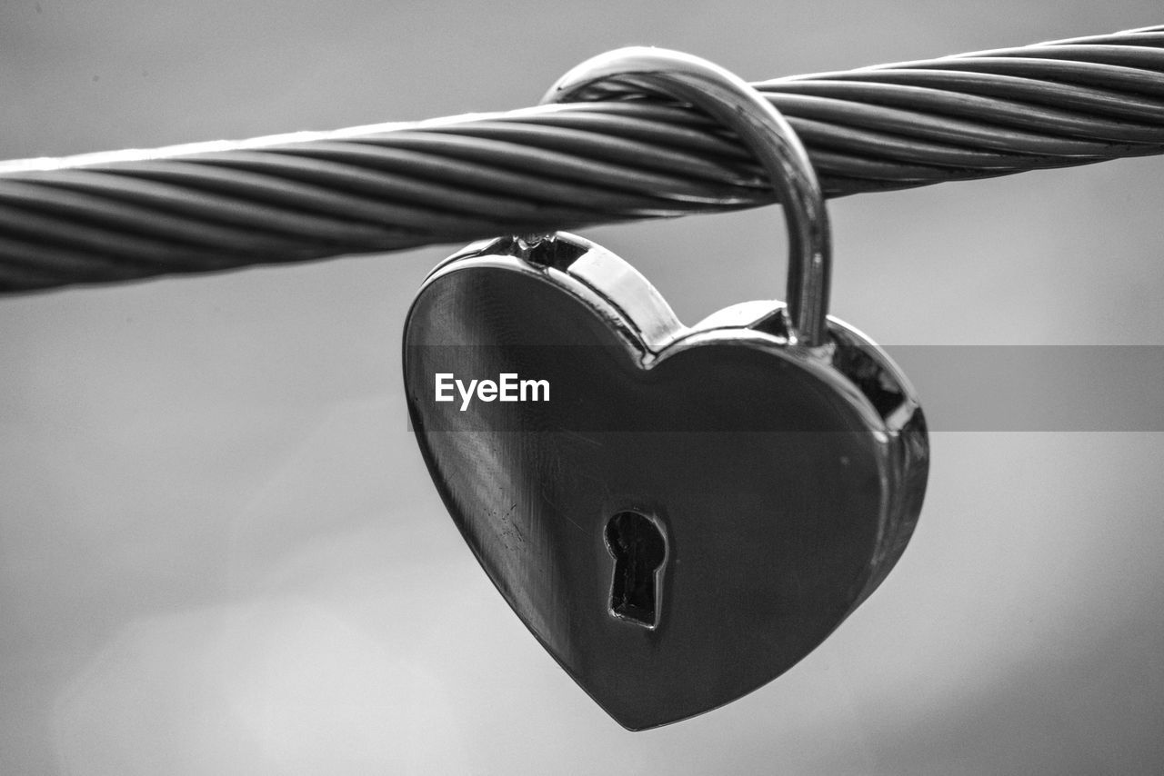 CLOSE-UP OF HEART SHAPE HANGING ON METAL AGAINST WALL