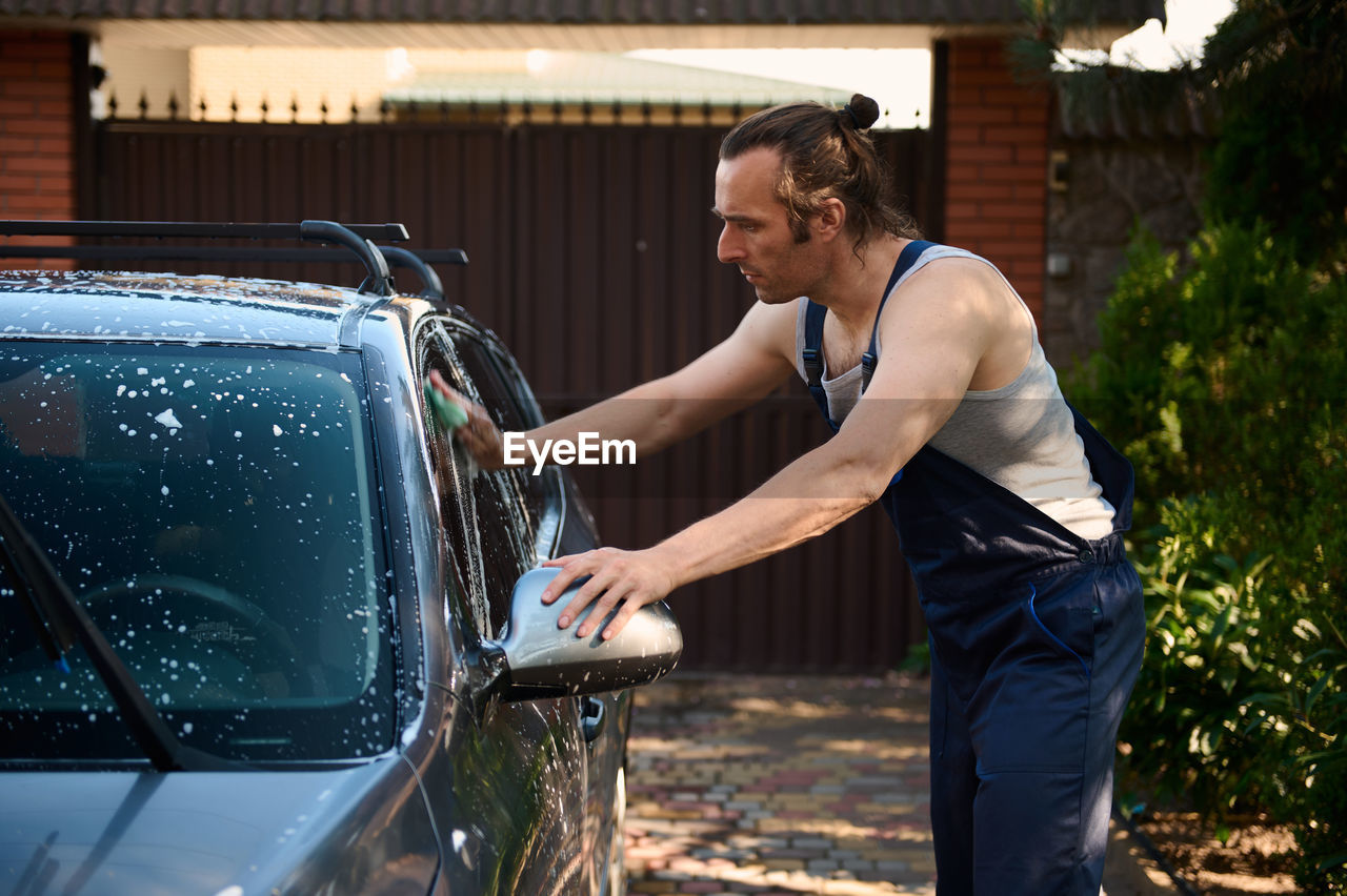 side view of man cleaning car