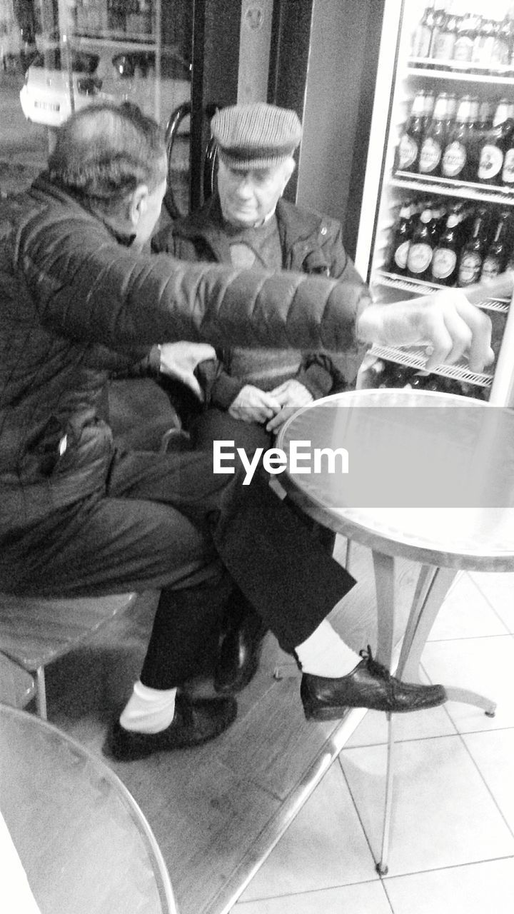 HIGH ANGLE VIEW OF PEOPLE SITTING ON CHAIR IN CAFE