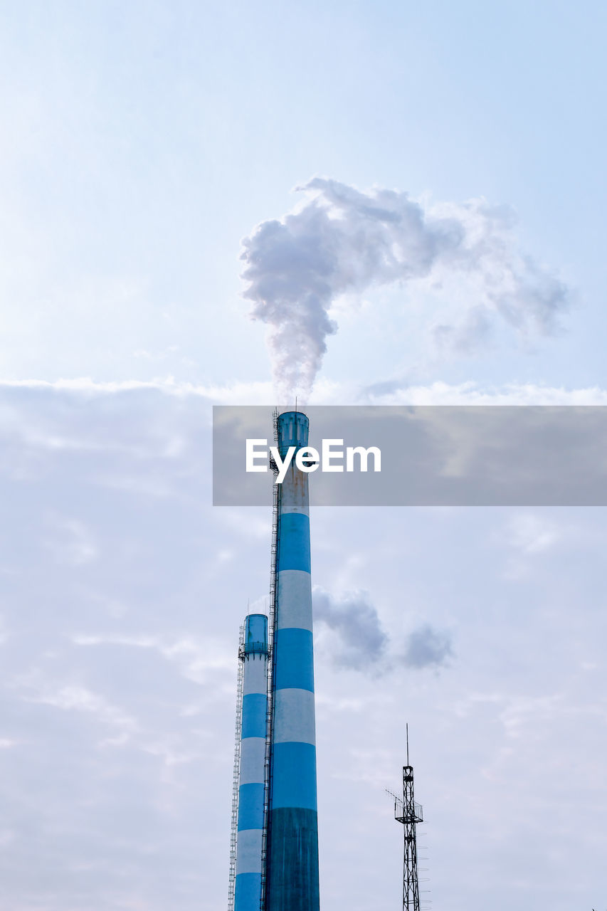 Low angle view of smoke emitting from chimney against sky