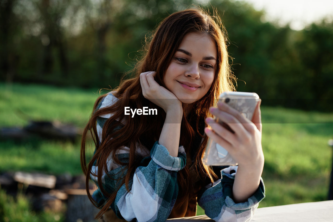 portrait of young woman using mobile phone outdoors