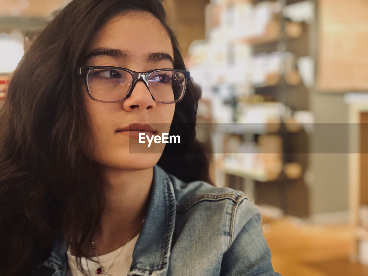 Close-up of young woman looking away while sitting at home