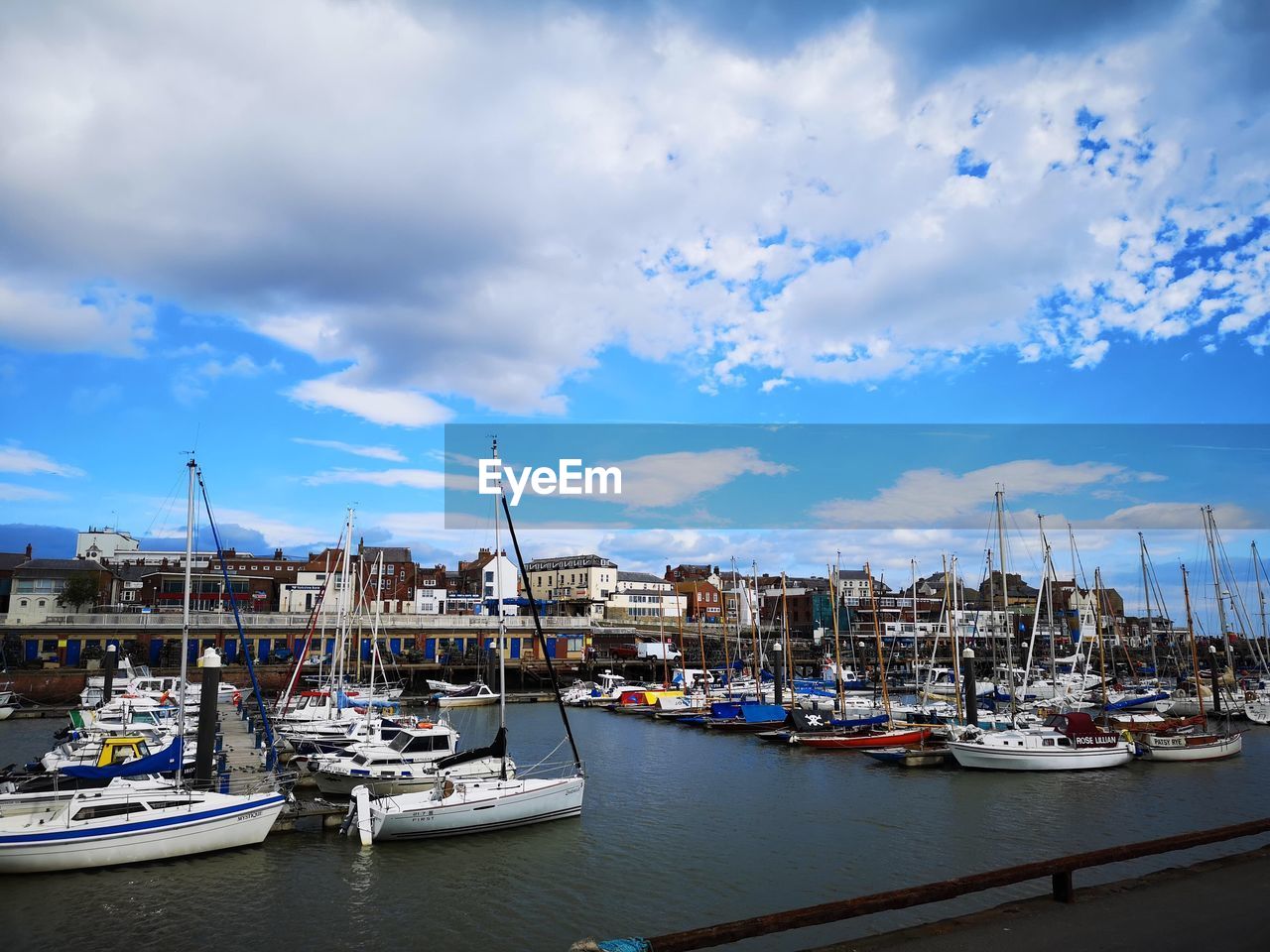 BOATS MOORED AT HARBOR AGAINST SKY