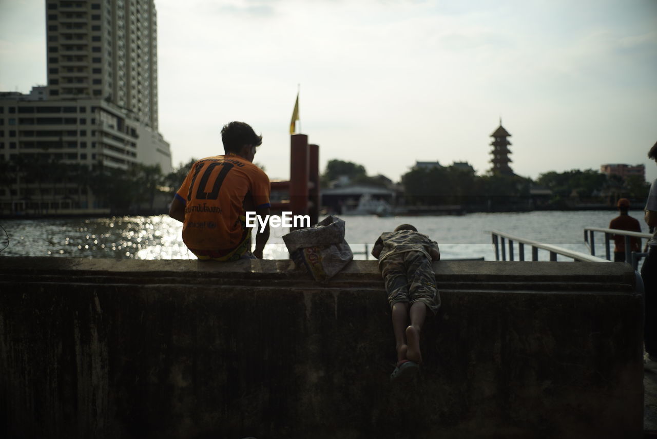 REAR VIEW OF MAN STANDING ON RIVER