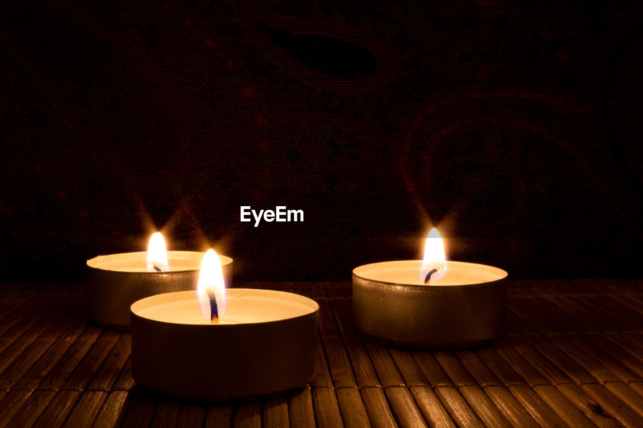 Close-up of three lit candles on table