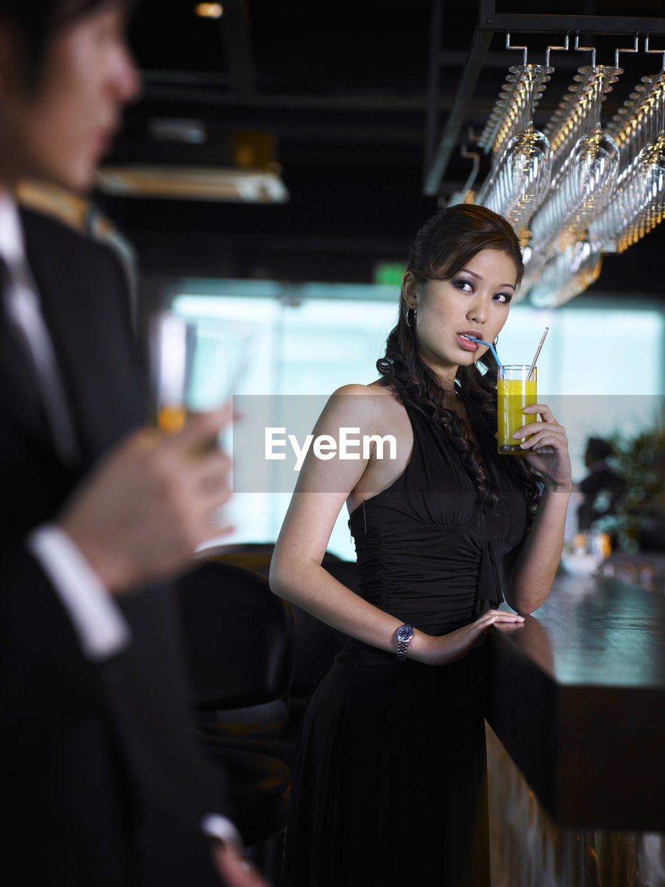 Young woman looking at businessman drinking at bar