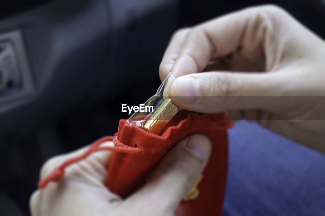 CLOSE-UP OF HAND HOLDING RED CHILI