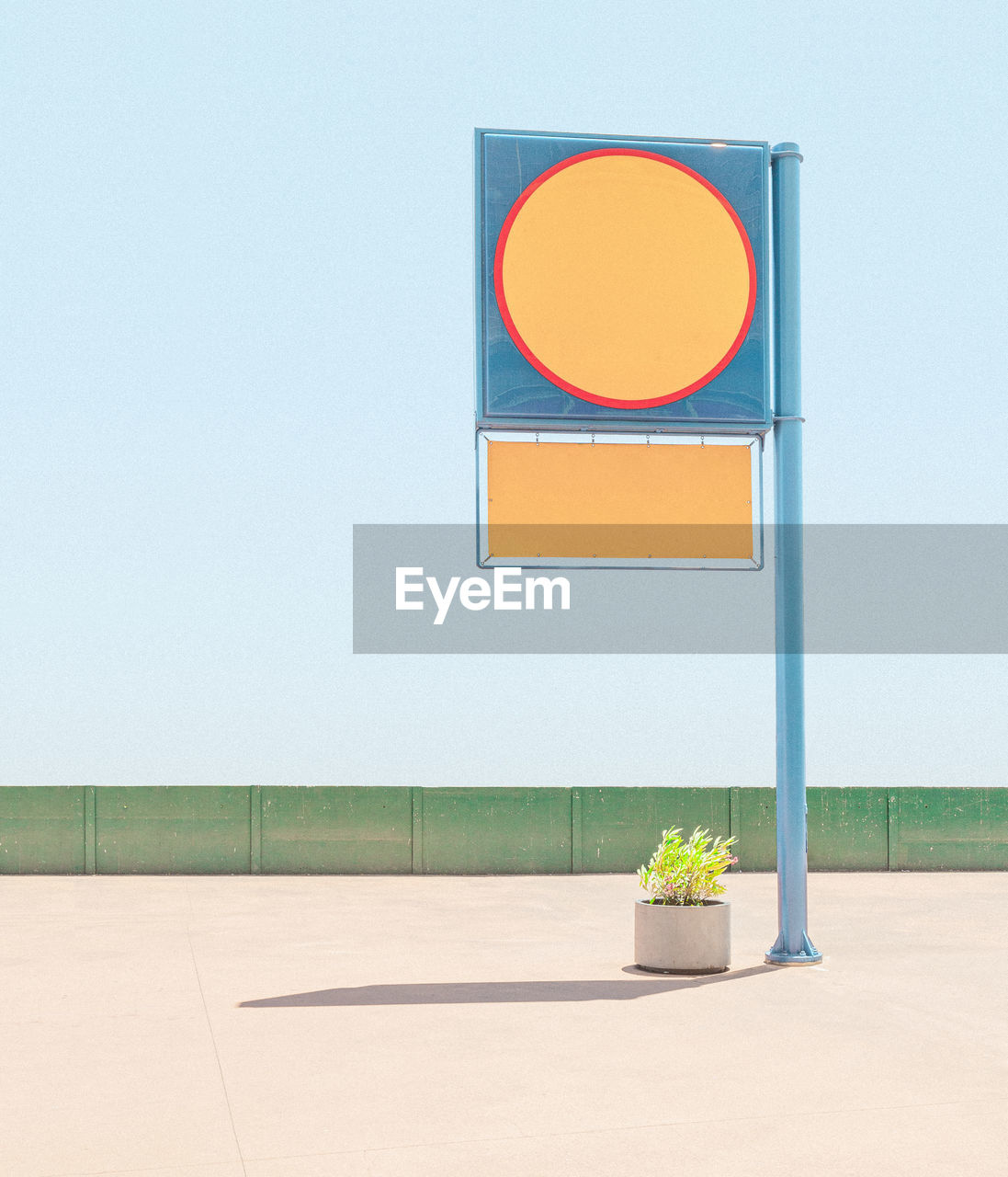 Potted plant under information sign against clear blue sky