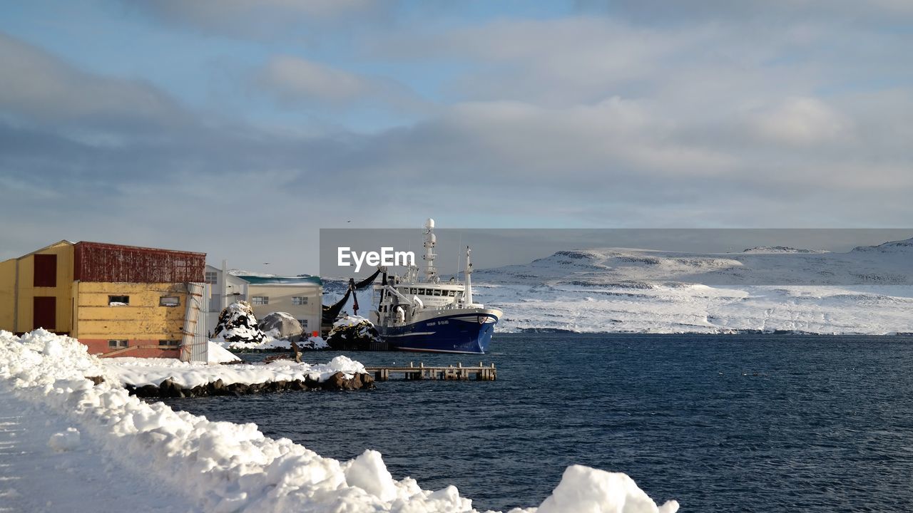 Ship moored in sea against cloudy sky during winter