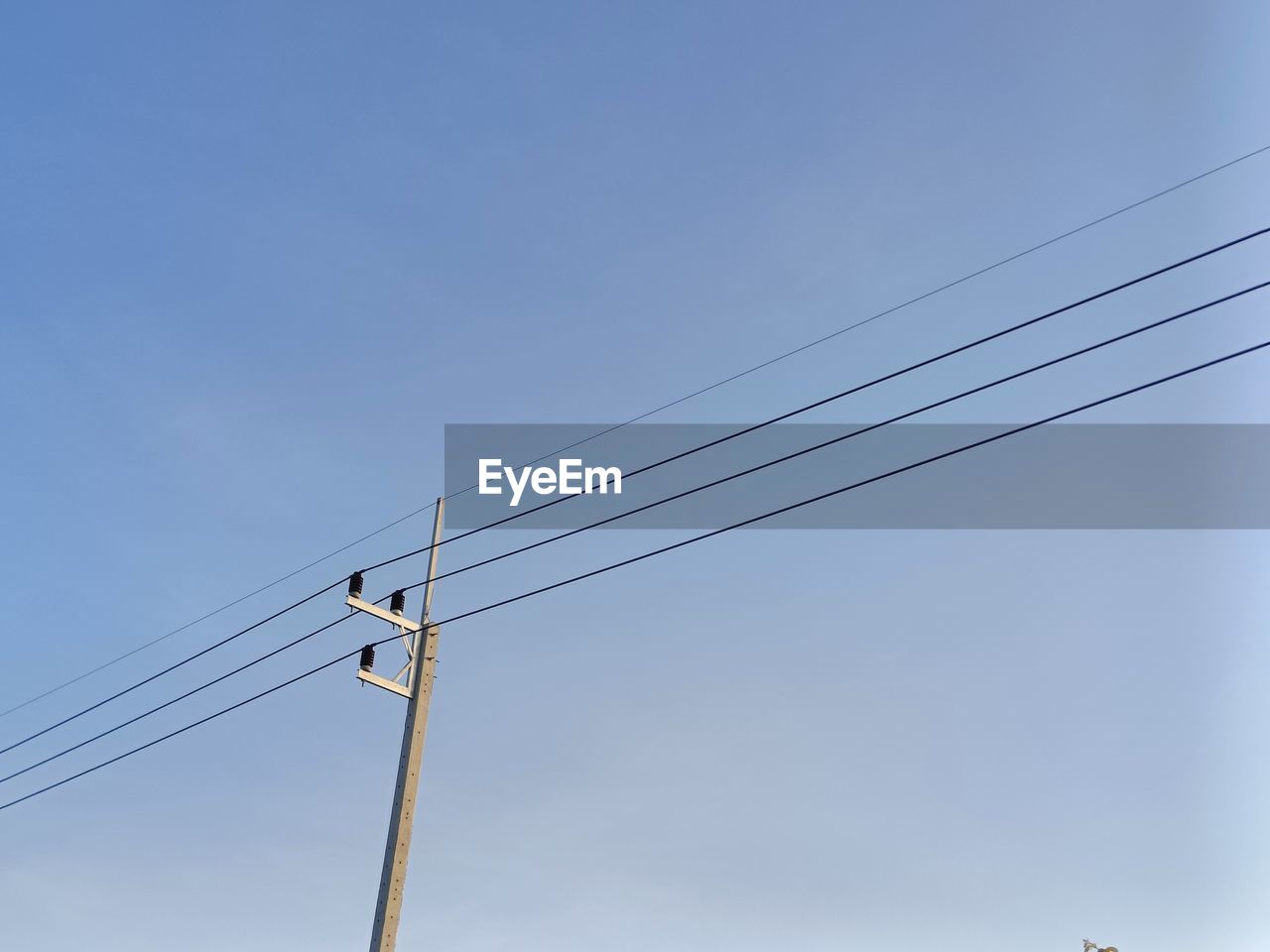 Low angle view of electricity pylon against clear sky