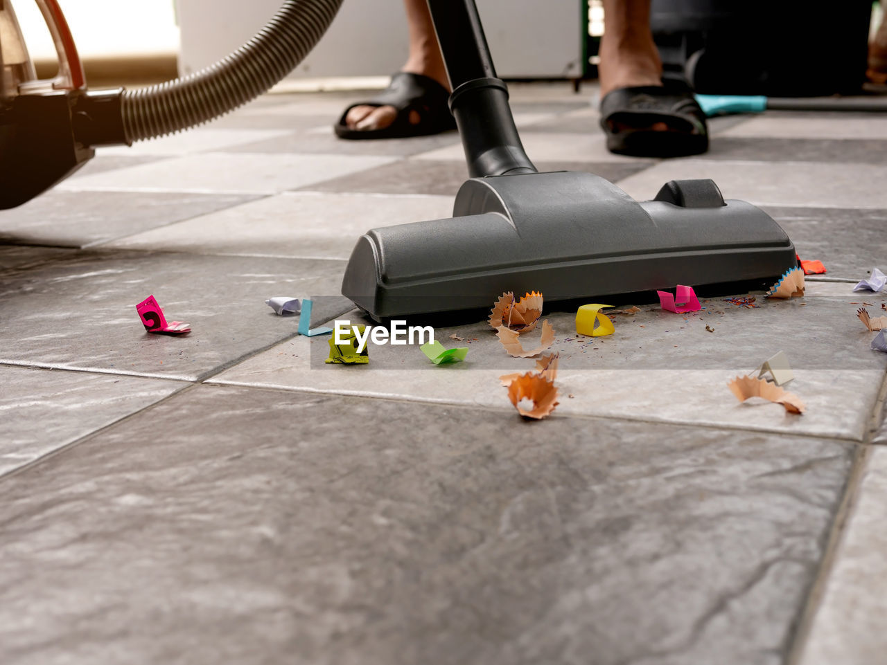 Sweep up paper scraps and dust on tile floors with a vacuum cleaner.