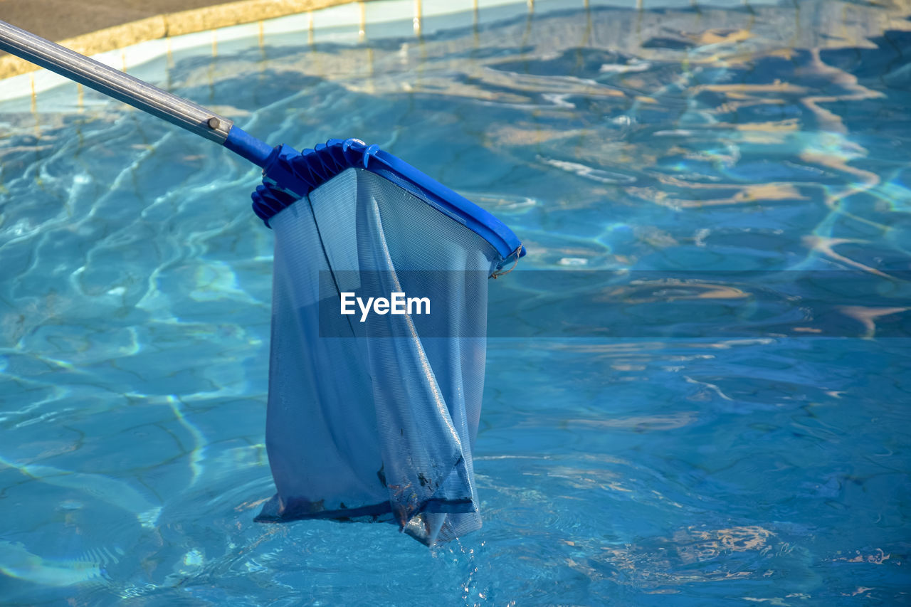 Cleaning pool from garbage with special net. clear water with blue tint.