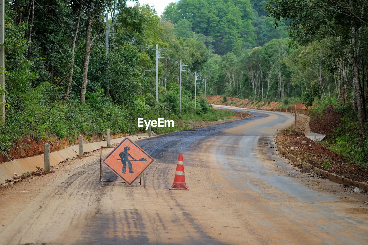 ROAD SIGN AMIDST TREES IN FOREST