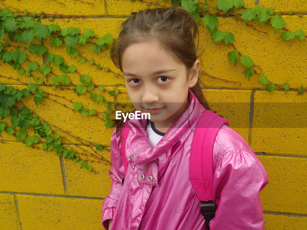 Portrait of girl standing by yellow wall