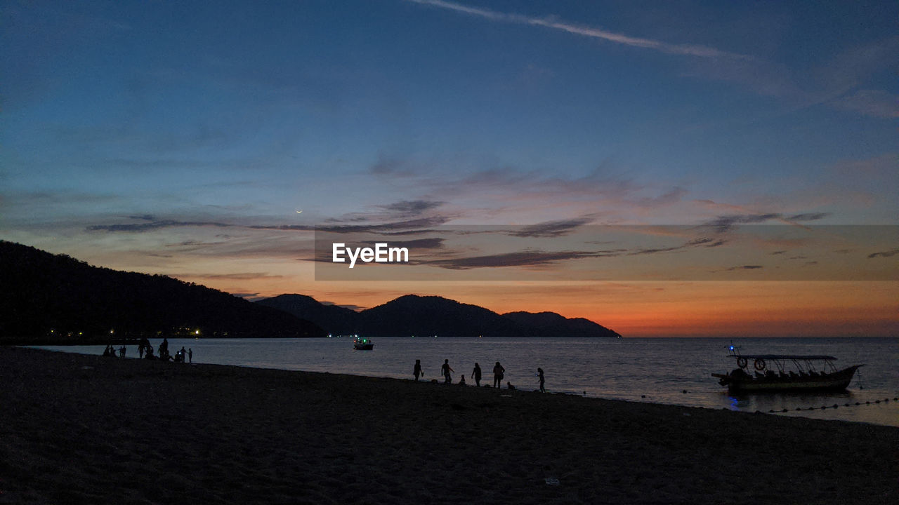 SCENIC VIEW OF BEACH AGAINST SKY AT SUNSET