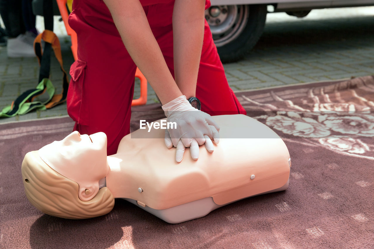 Midsection of rescue worker performing cpr on mannequin