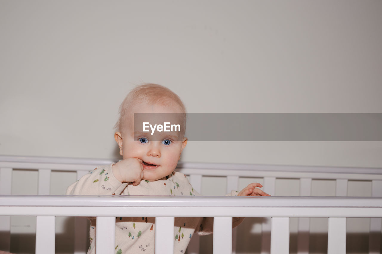 Close-up of a cute baby standing in his cot