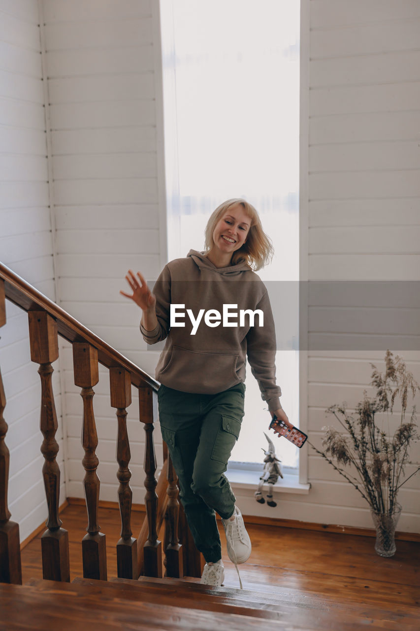 Portrait of a smiling young woman standing against railing