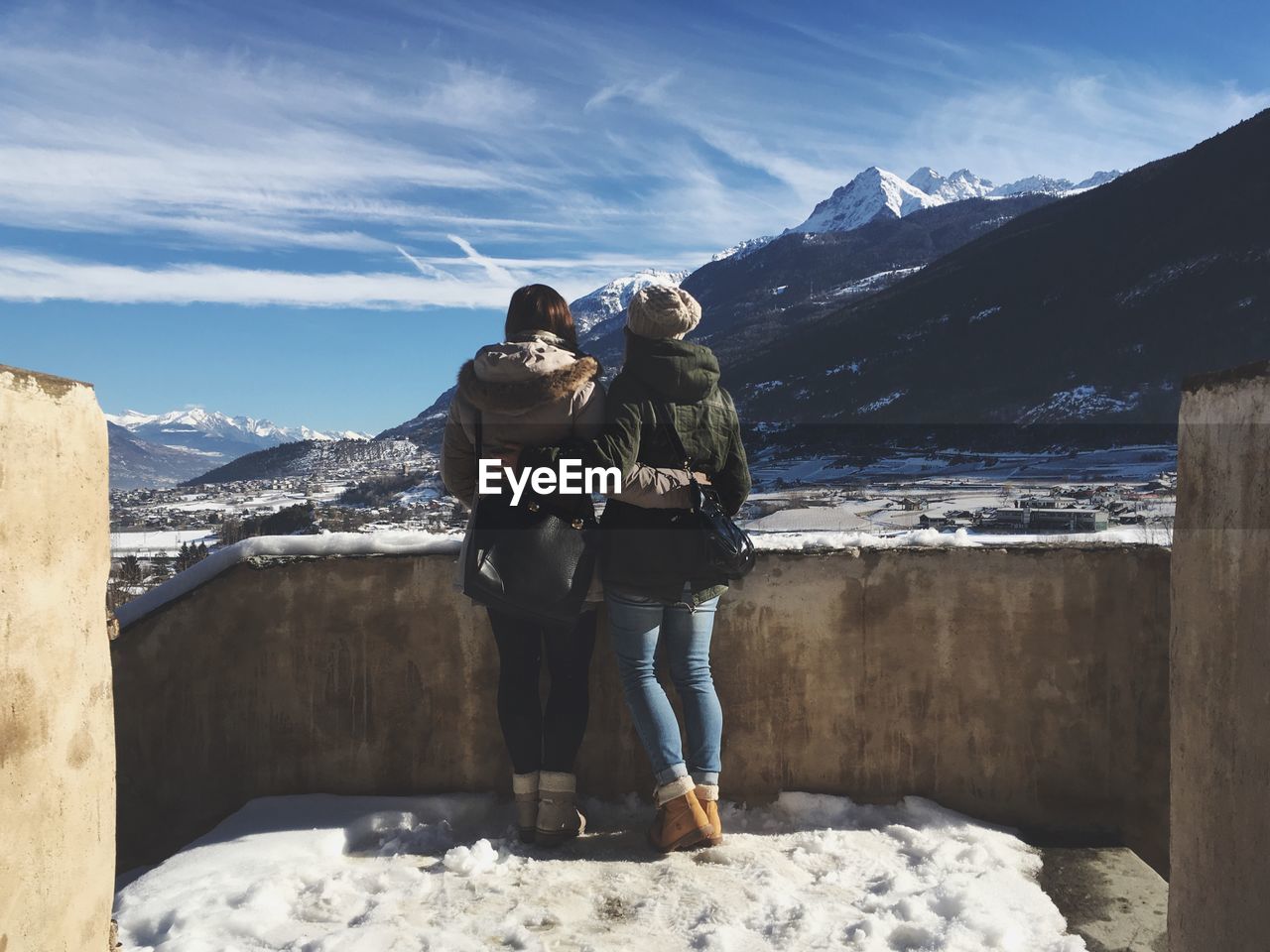 Rear view of female friends standing against snowcapped mountain