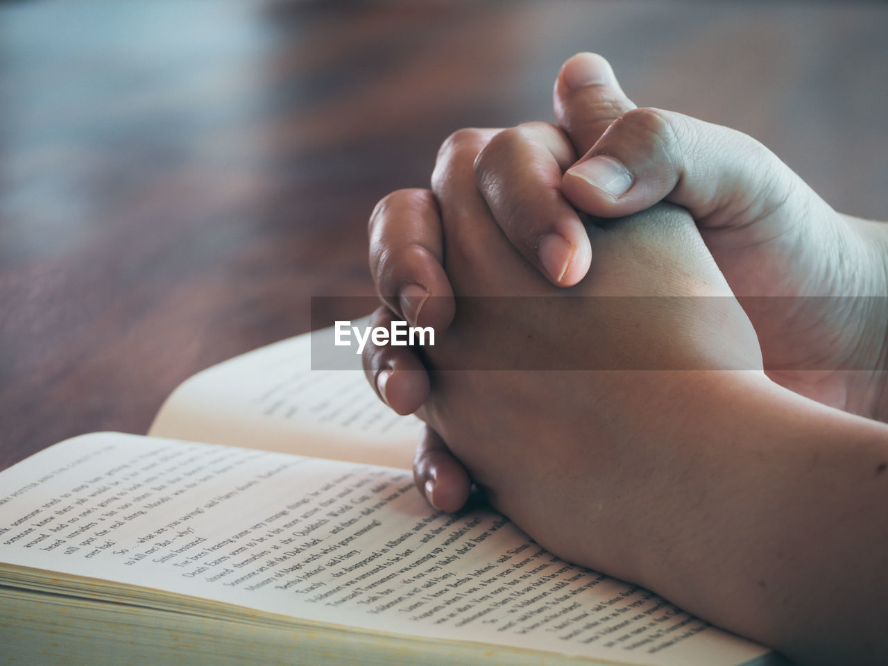 Cropped image of person with hands clasped on book