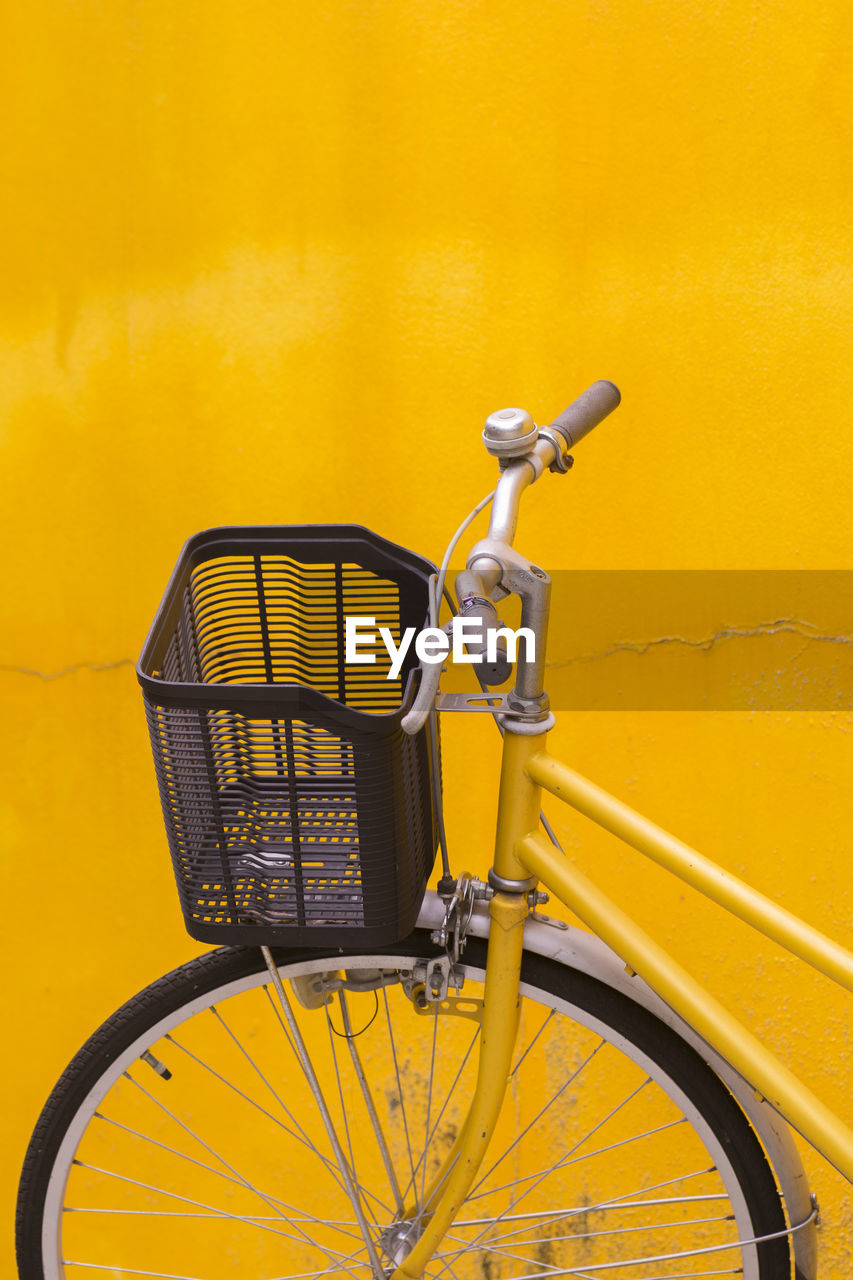 Bicycle parked against yellow wall