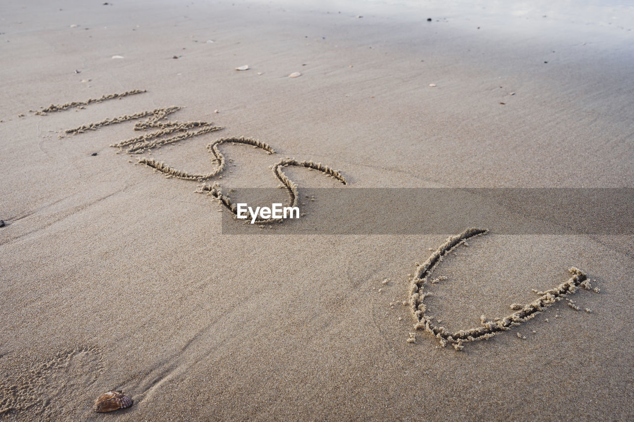 HIGH ANGLE VIEW OF TEXT ON HEART SHAPE ON BEACH