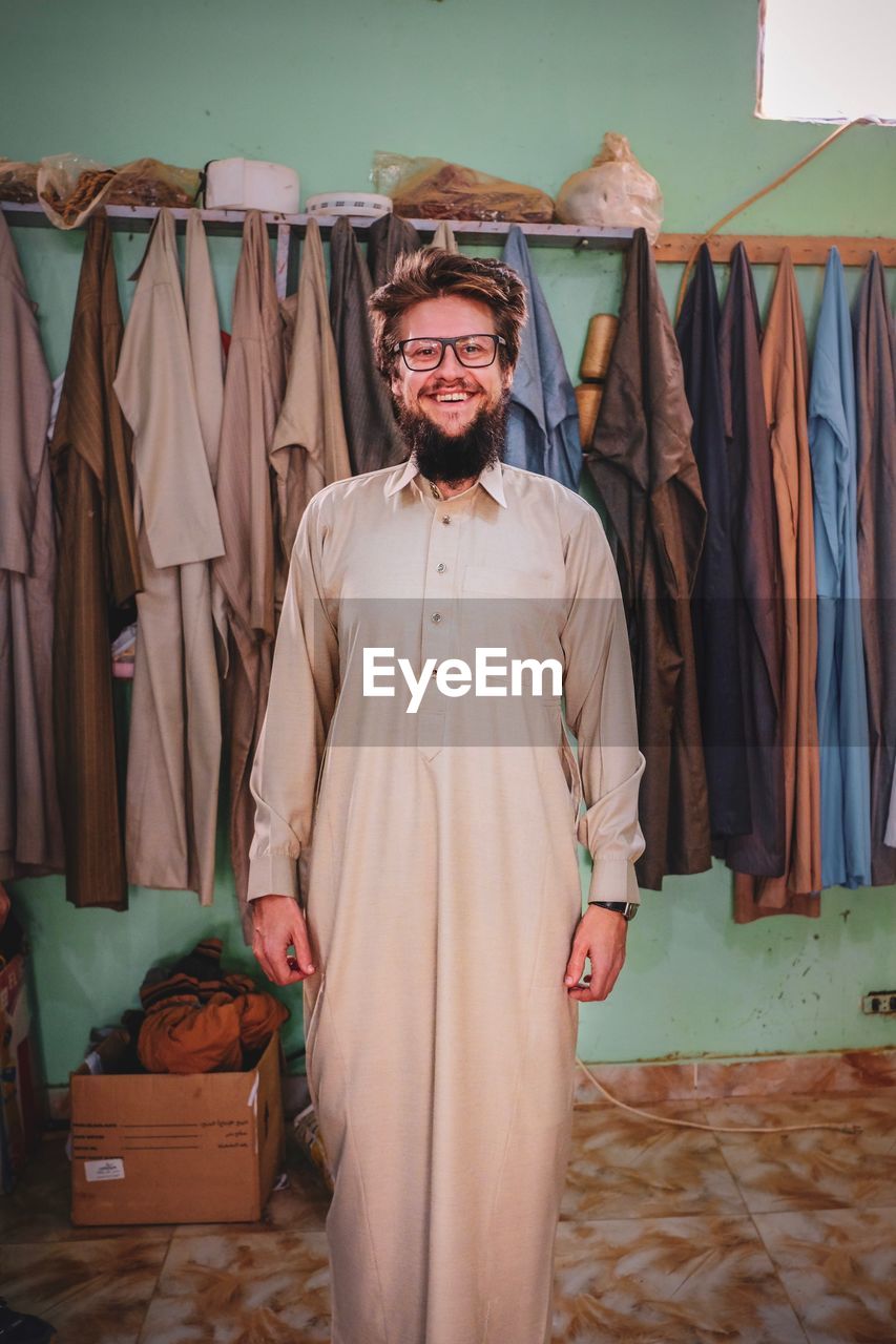 Portrait of smiling man wearing traditional clothing while standing at home