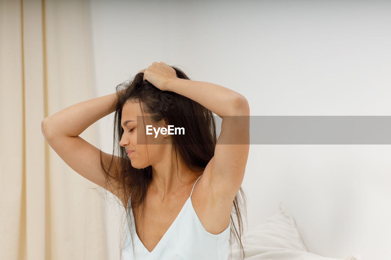 side view of young woman standing against wall