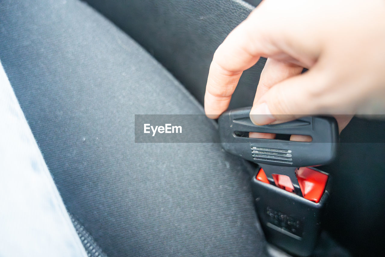 cropped hands of man using mobile phone while sitting in car