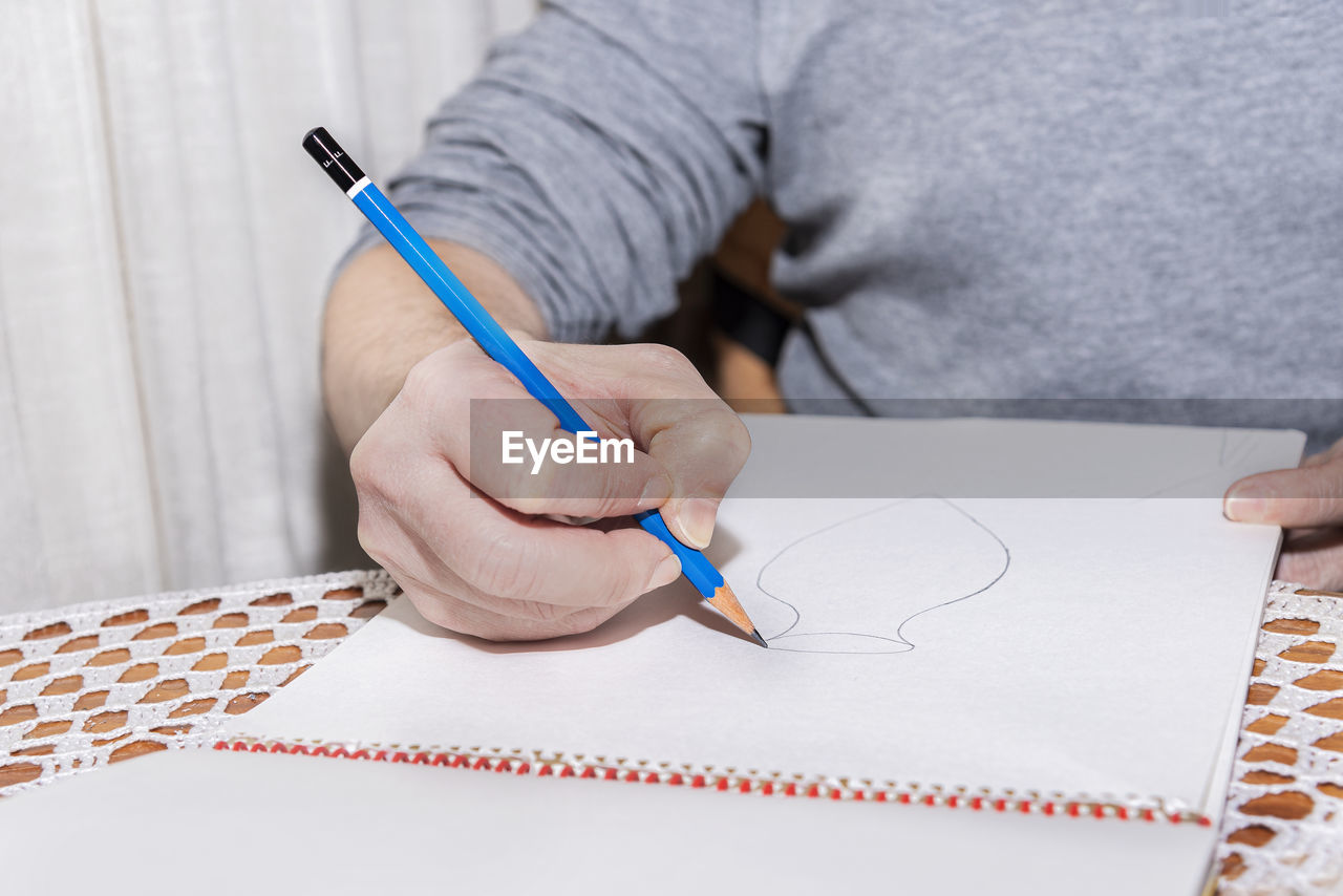 CLOSE-UP OF MAN HOLDING PAPER WITH PEN