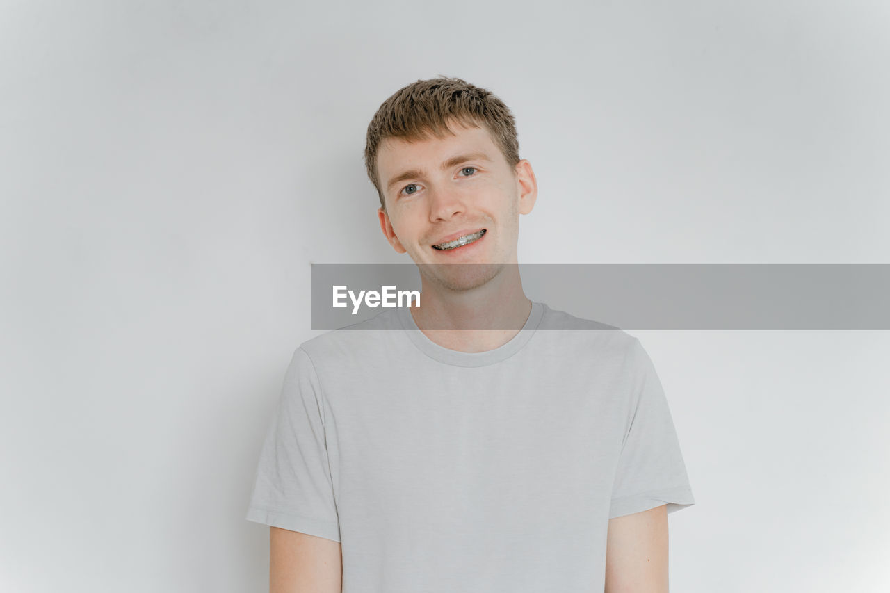 portrait of smiling young man standing against white background