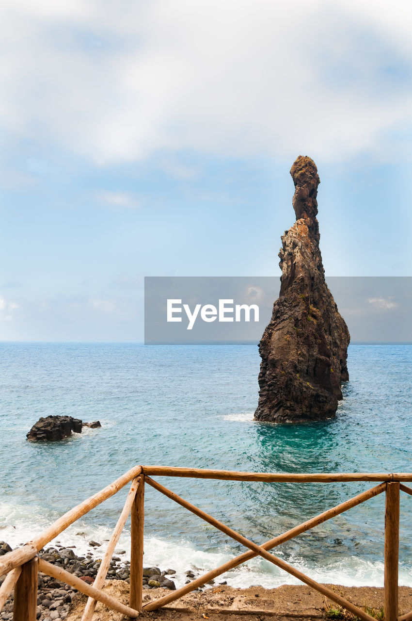 Rock formation by sea against sky