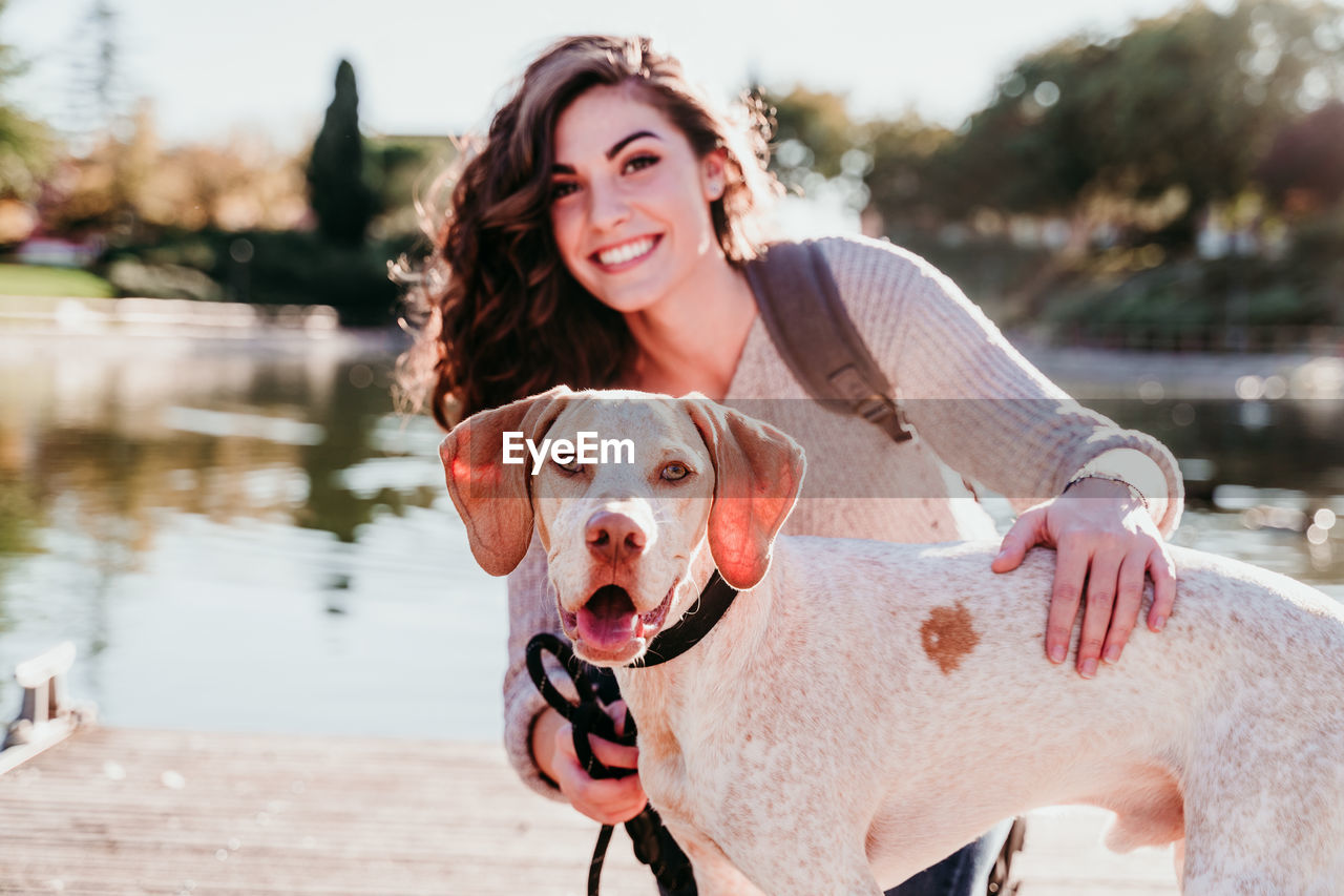 Woman with dog on pier over lake against trees