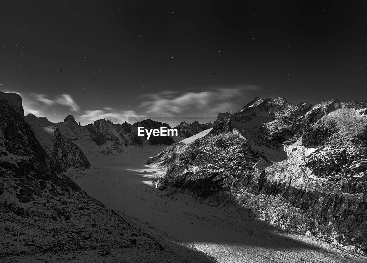 Scenic view of snowcapped mountains against sky at night