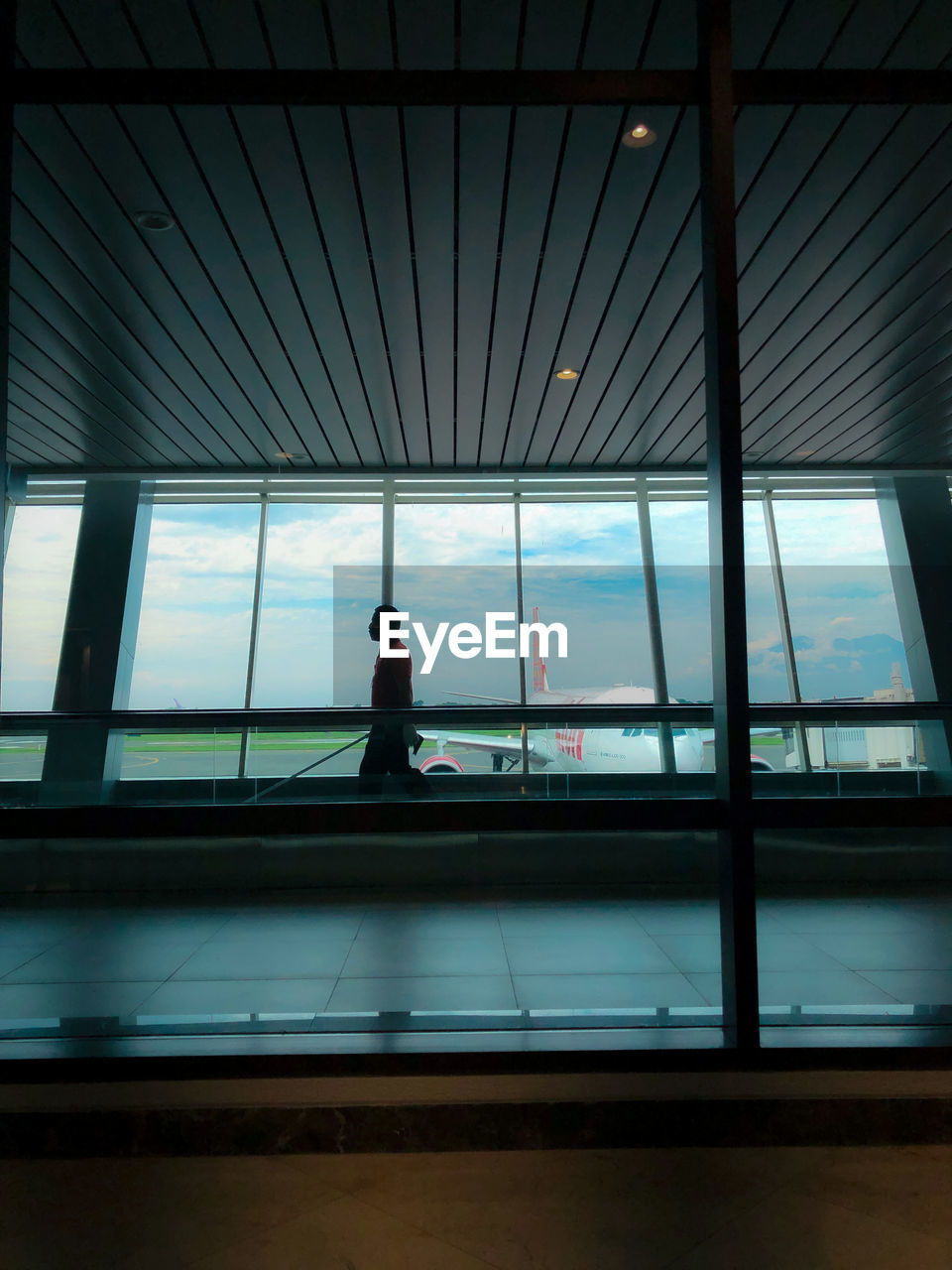 SILHOUETTE MAN STANDING AT AIRPORT WINDOW