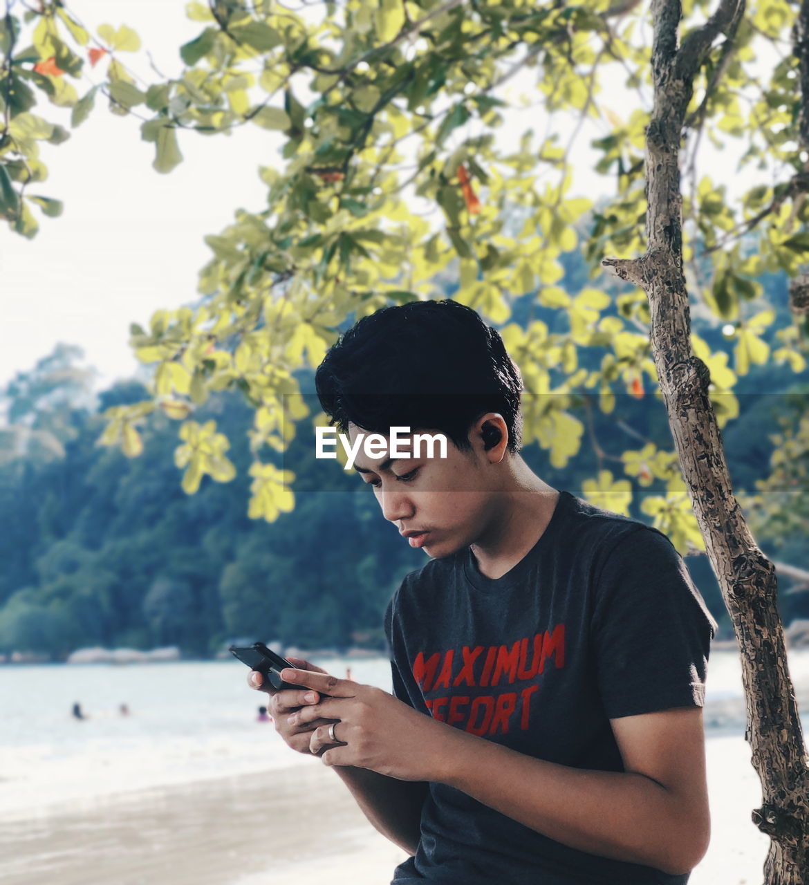 Young man using phone while standing outdoors