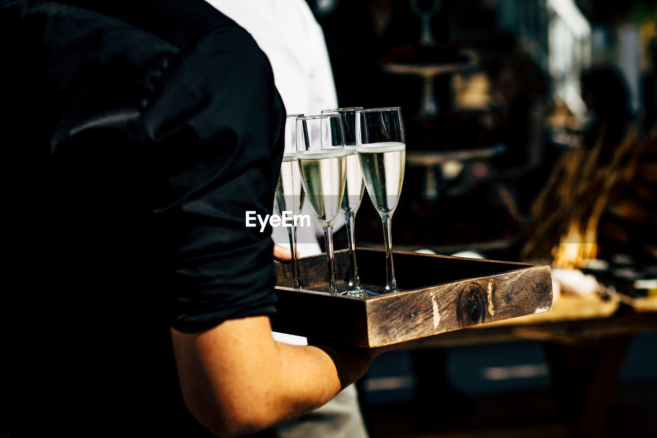 Rear view of waiter holding wine glass at restaurant