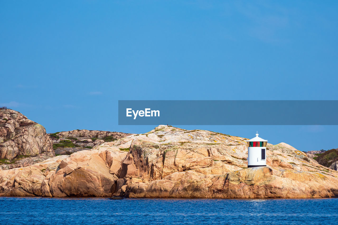 LIGHTHOUSE BY SEA AGAINST CLEAR SKY