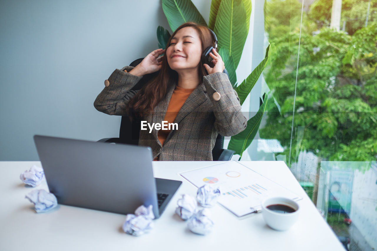 portrait of young woman using laptop while sitting on table