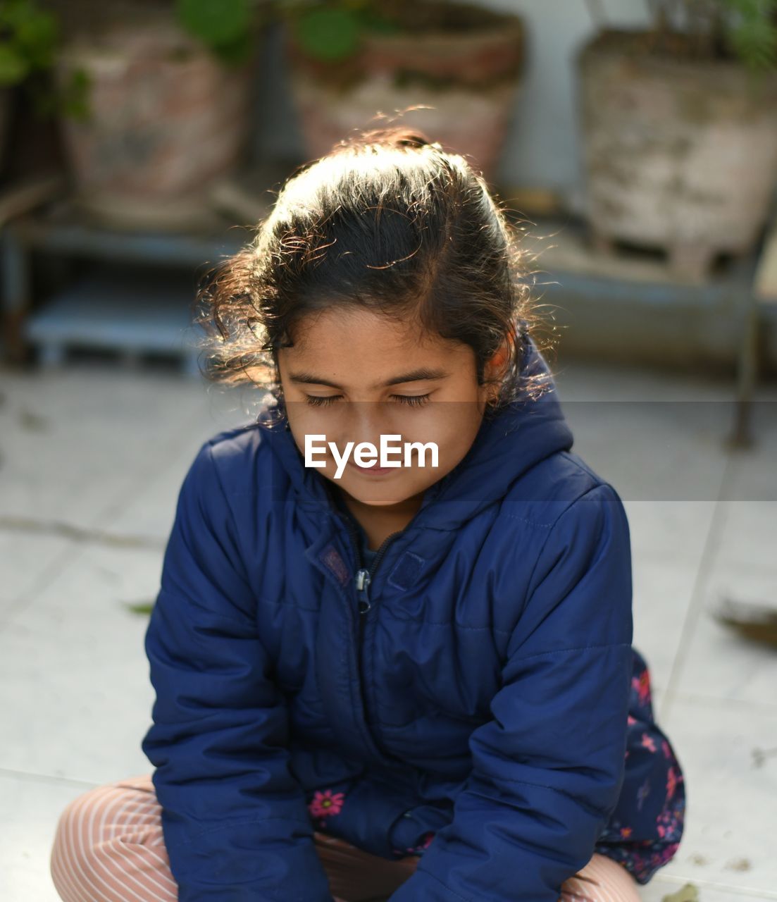 Smiling girl with closed eyes sitting outdoors