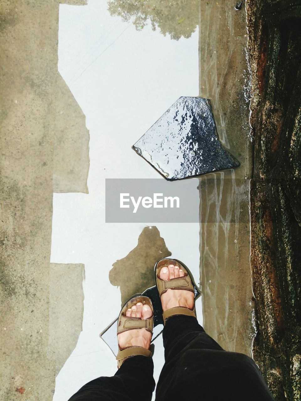 Low section of man walking in puddle