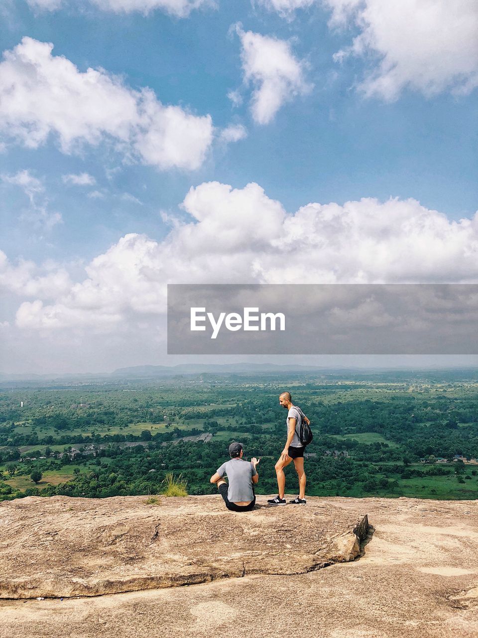 REAR VIEW OF PEOPLE WALKING ON MOUNTAIN AGAINST SKY