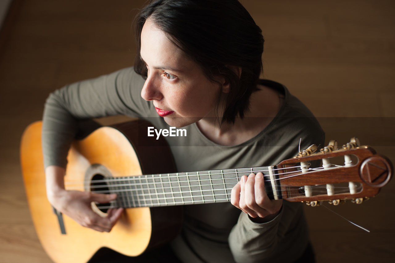 Young woman looking away while playing guitar