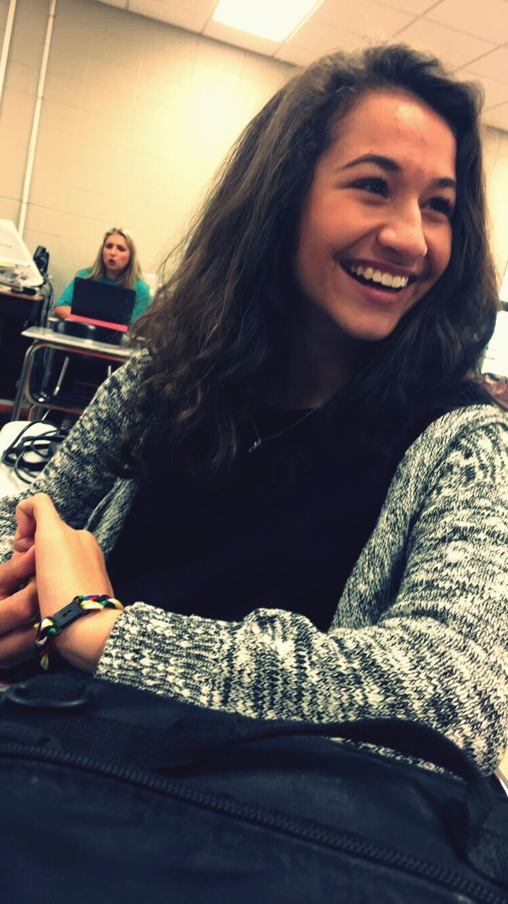 PORTRAIT OF A SMILING YOUNG WOMAN SITTING ON FLOOR