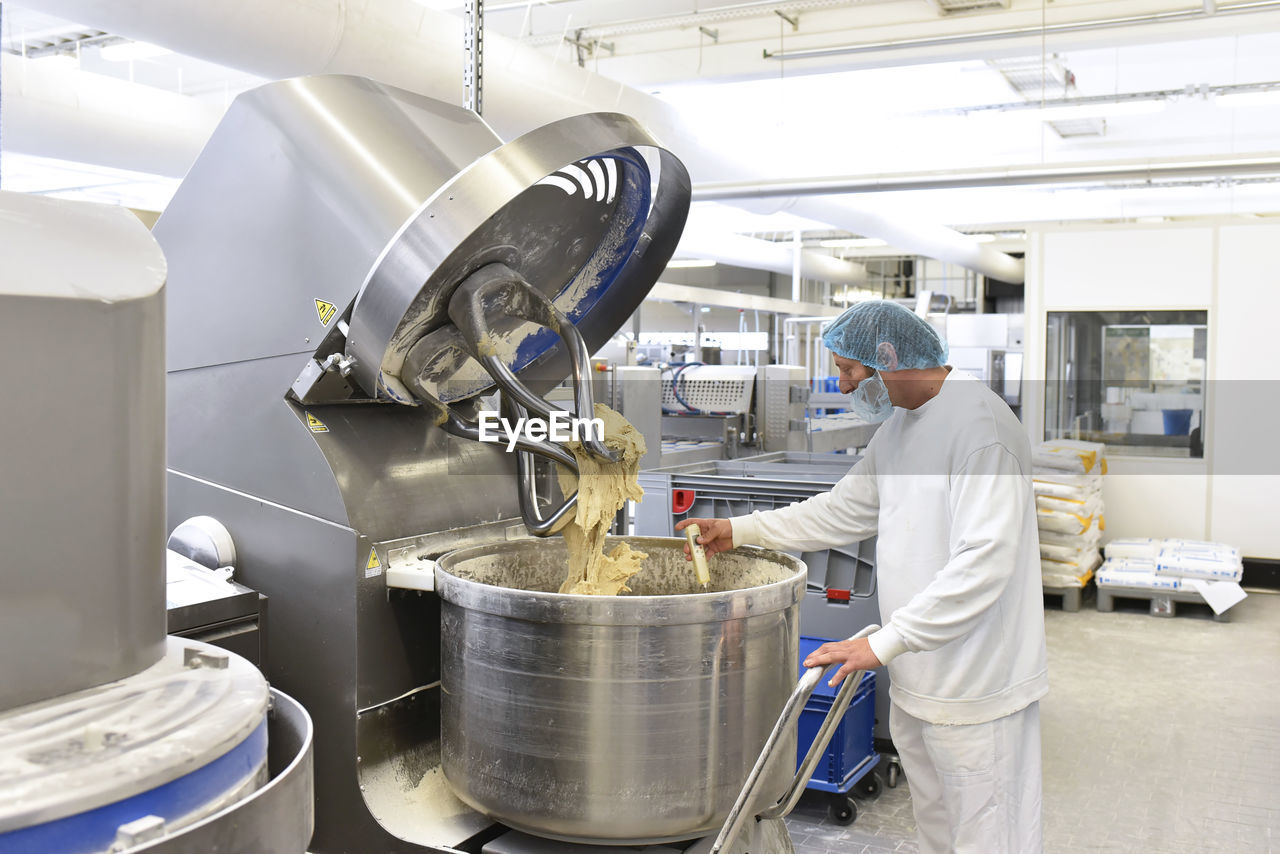 Worker at dough kneading machine in an industrial bakery