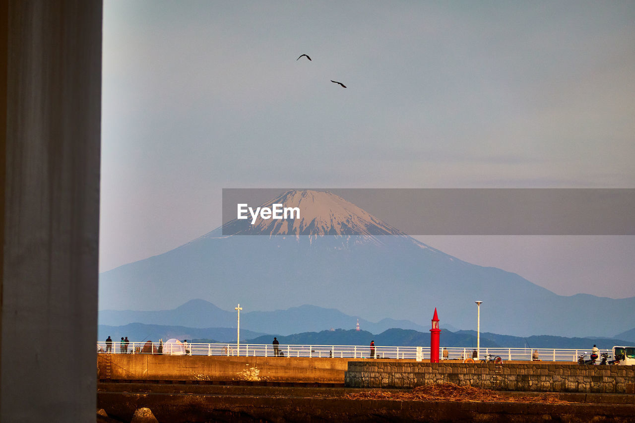 mountain, horizon, sky, morning, nature, bird, beauty in nature, dawn, travel destinations, scenics - nature, flying, sea, land, architecture, volcano, animal themes, no people, landscape, animal wildlife, water, animal, travel, outdoors, sunrise, transportation, wildlife, built structure, environment, day, tranquil scene, mountain range, tranquility, cloud, coast, building exterior