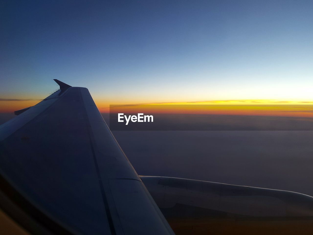 Cropped image of airplane flying in sea at sunset