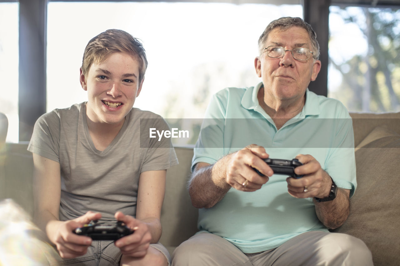 Grandfather and grandson playing video game on couch at home